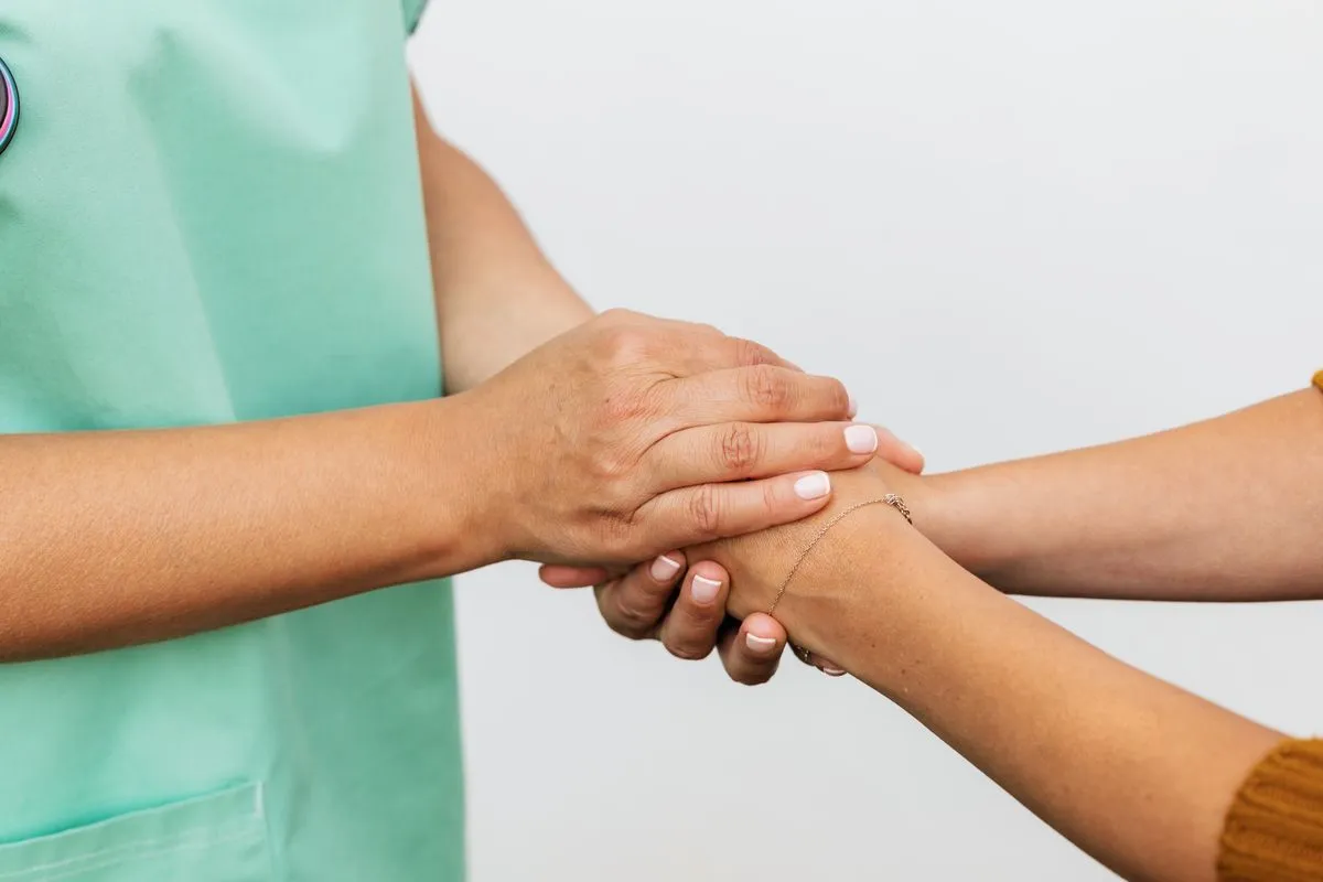 Soignante tenant la main d'une personne, geste de soin et d'accompagnement